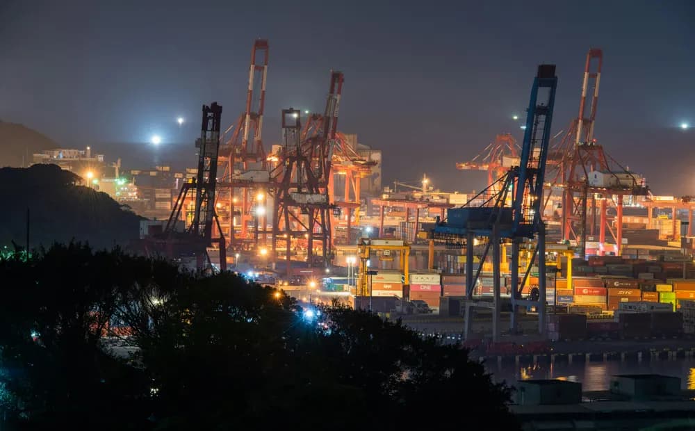 Terminal portuaria iluminada de noche con grúas de contenedores