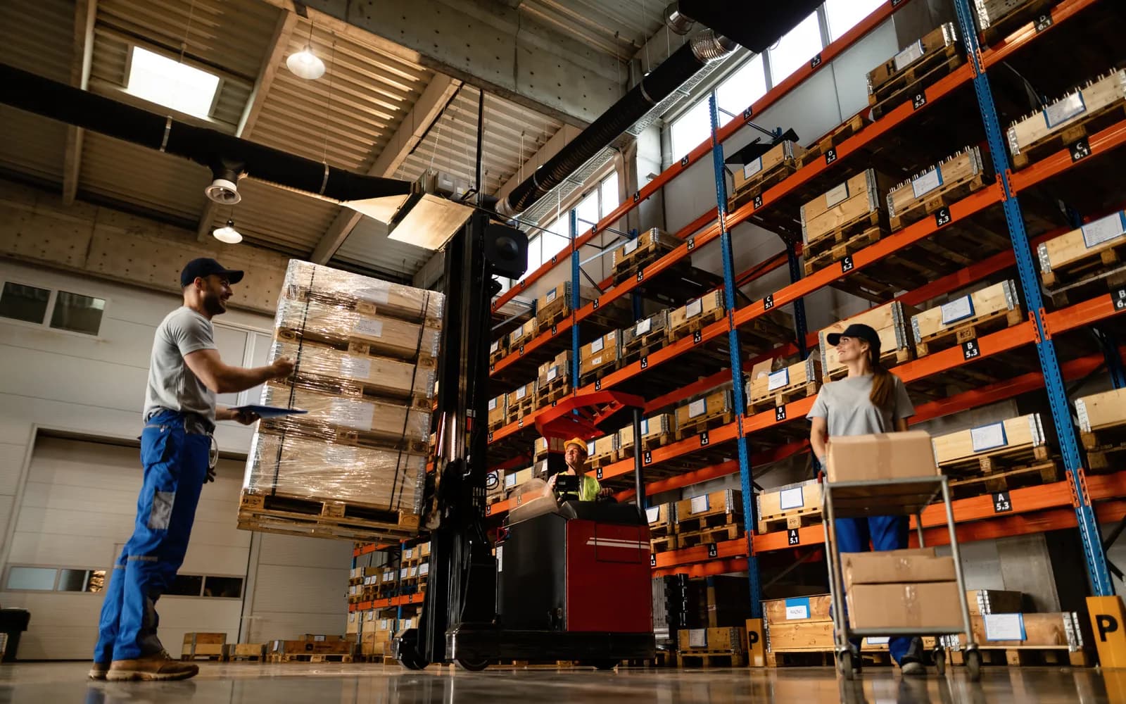 Trabajadores de bodega coordinando mercancía en estanterías de almacenamiento industrial